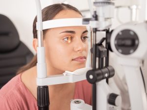woman wearing contacts behind slit lamp 300x225