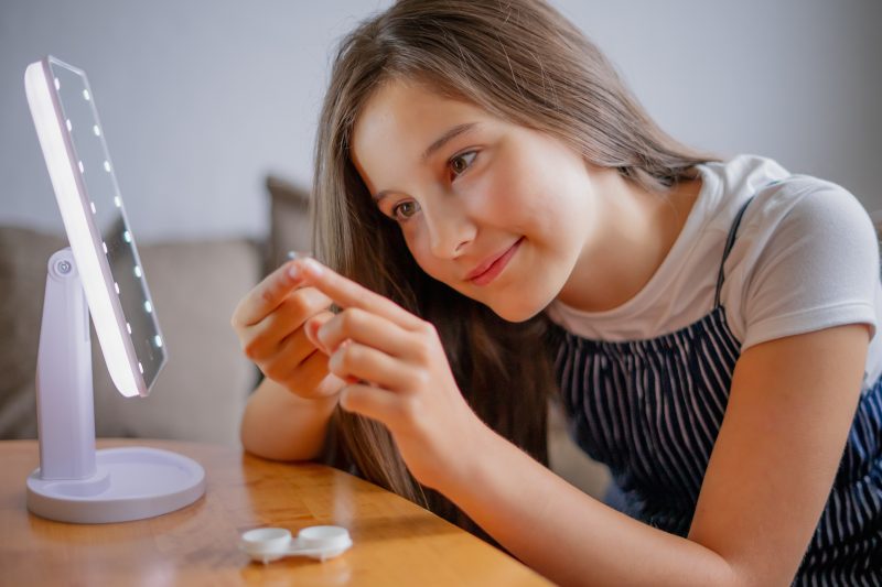 young girl putting on contact lens