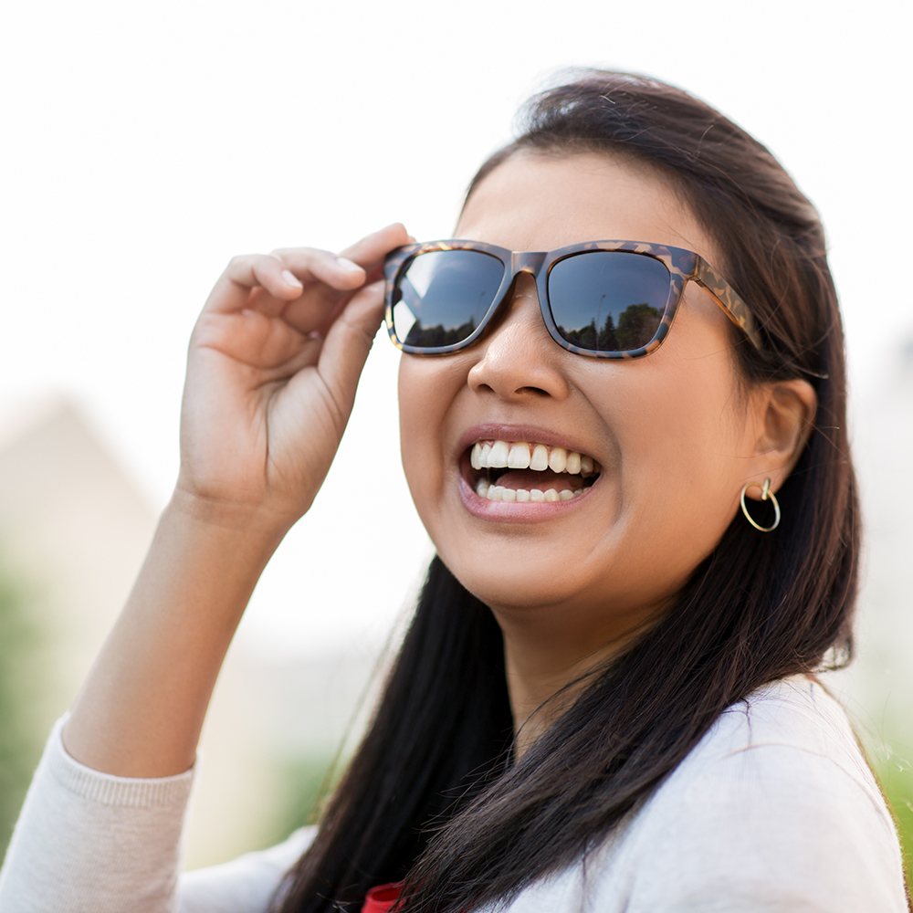 portrait of happy smiling young woman in sunglasses outdoors
