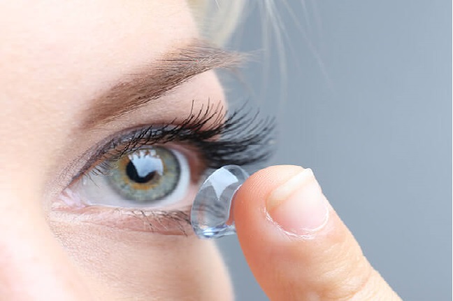 woman inserting a contact lens into her eye