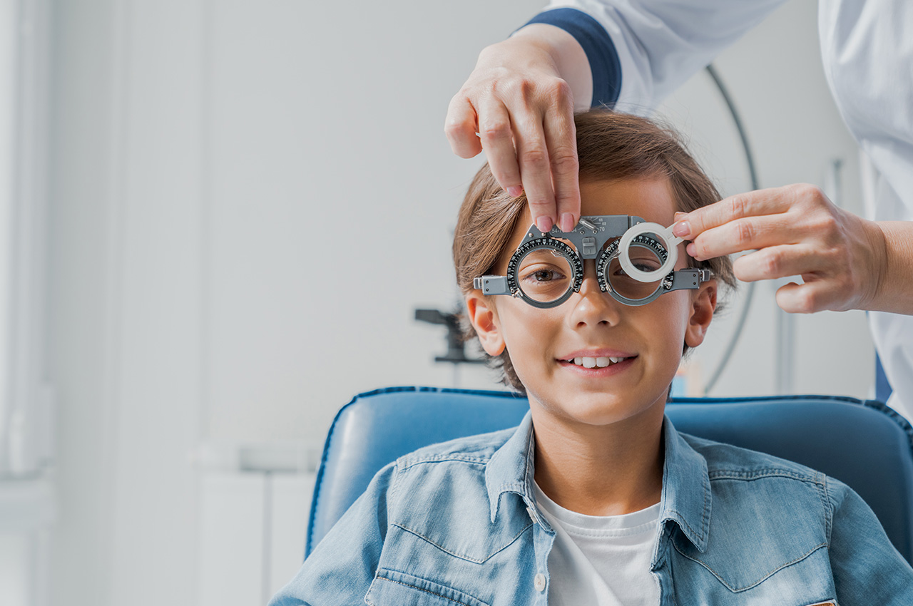 Child boy in glasses checks eye vision at pediatric ophthalmologist