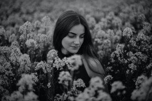 photo of woman sitting in black and white flower field 