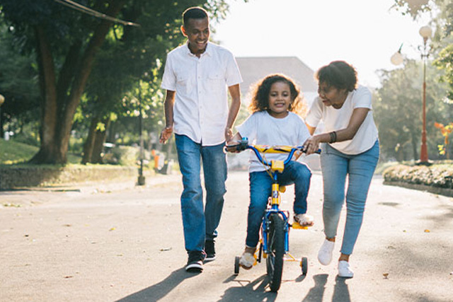 girl on a bike with her parents