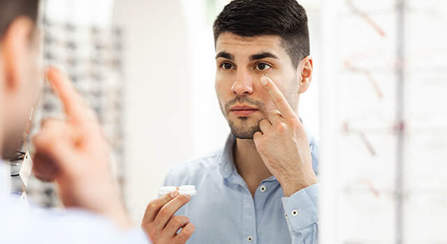 man holding a contact lens on his finger
