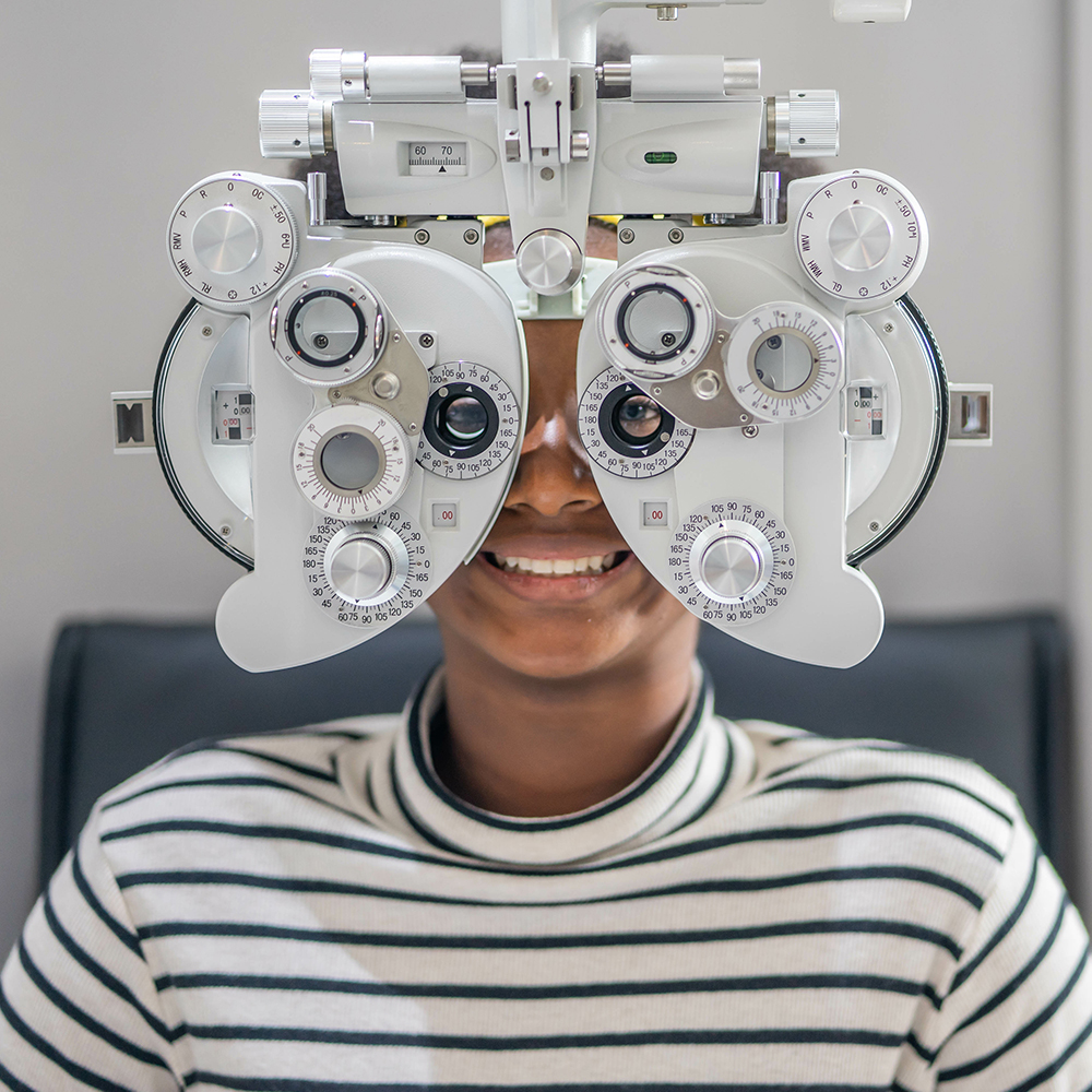Close up Of african teen girl Doing Eye Test On Phoropter, African teen girl checking on her eye with optometry machine.