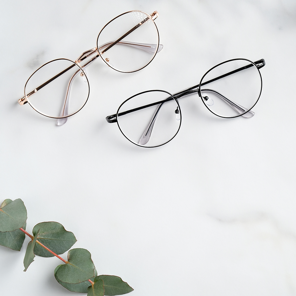 Womans eyeglasses and eucalyptus branches on marble background. Flat lay, top view.